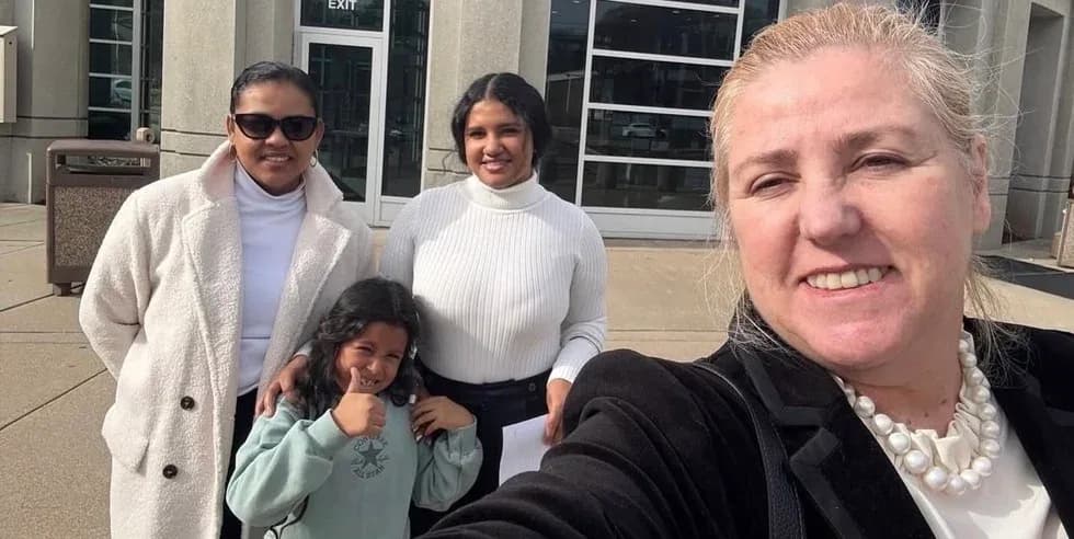 Maria Eijo takes a selfie with two women and a child giving a thumbs-up, outside a courthouse.