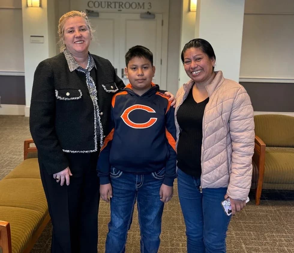 Maria Eijo stands with a boy and a woman in front of a doorway marked "Courtroom 3."